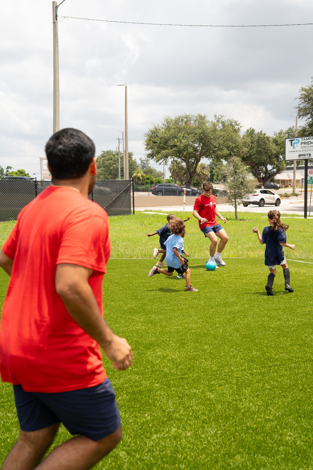 Coach playing soccer with kids on the field